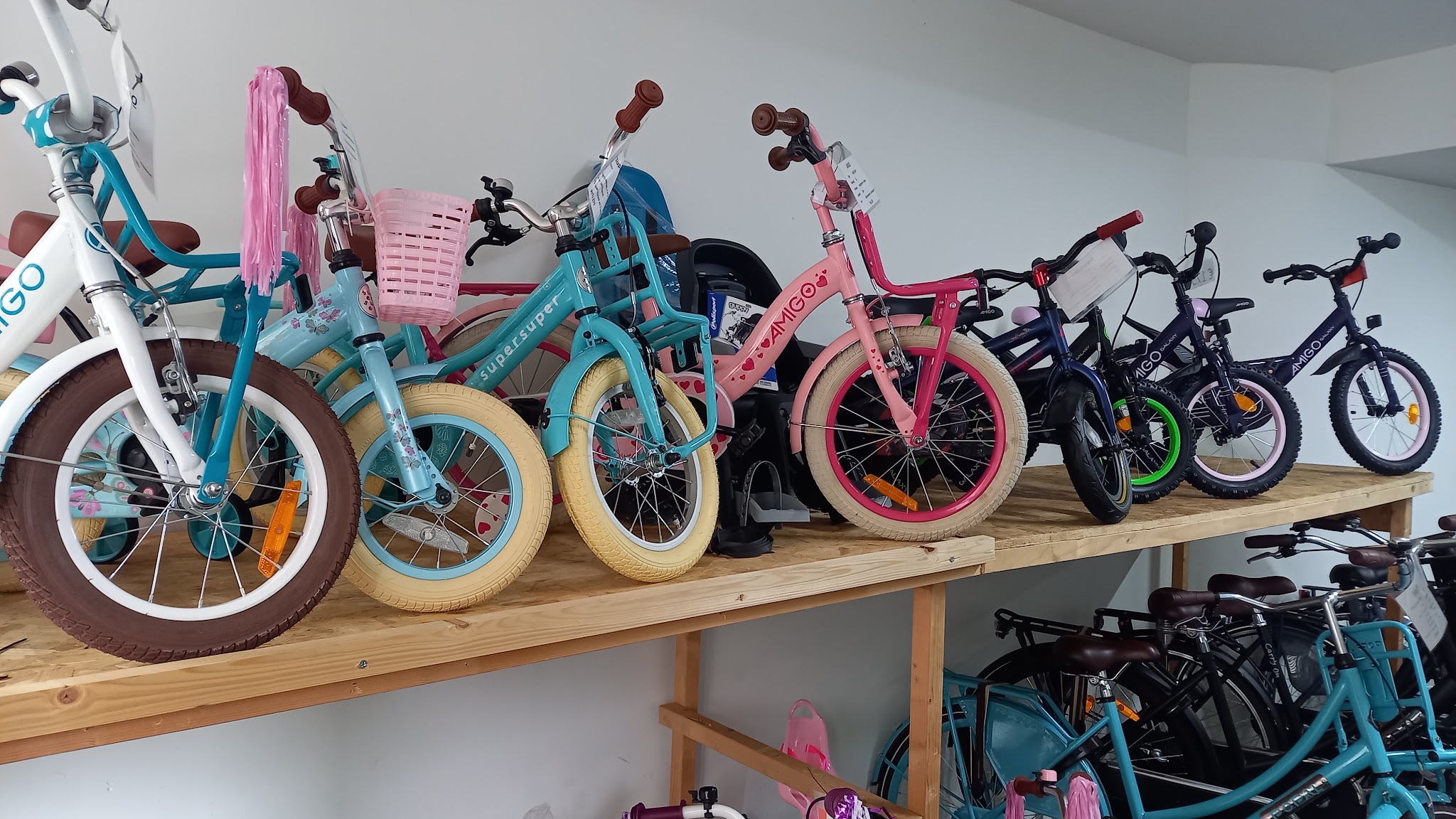 Nieuwe kinderfietsen van AMIGO en Supersuper op een houten stelling boven de stadsfietsen
