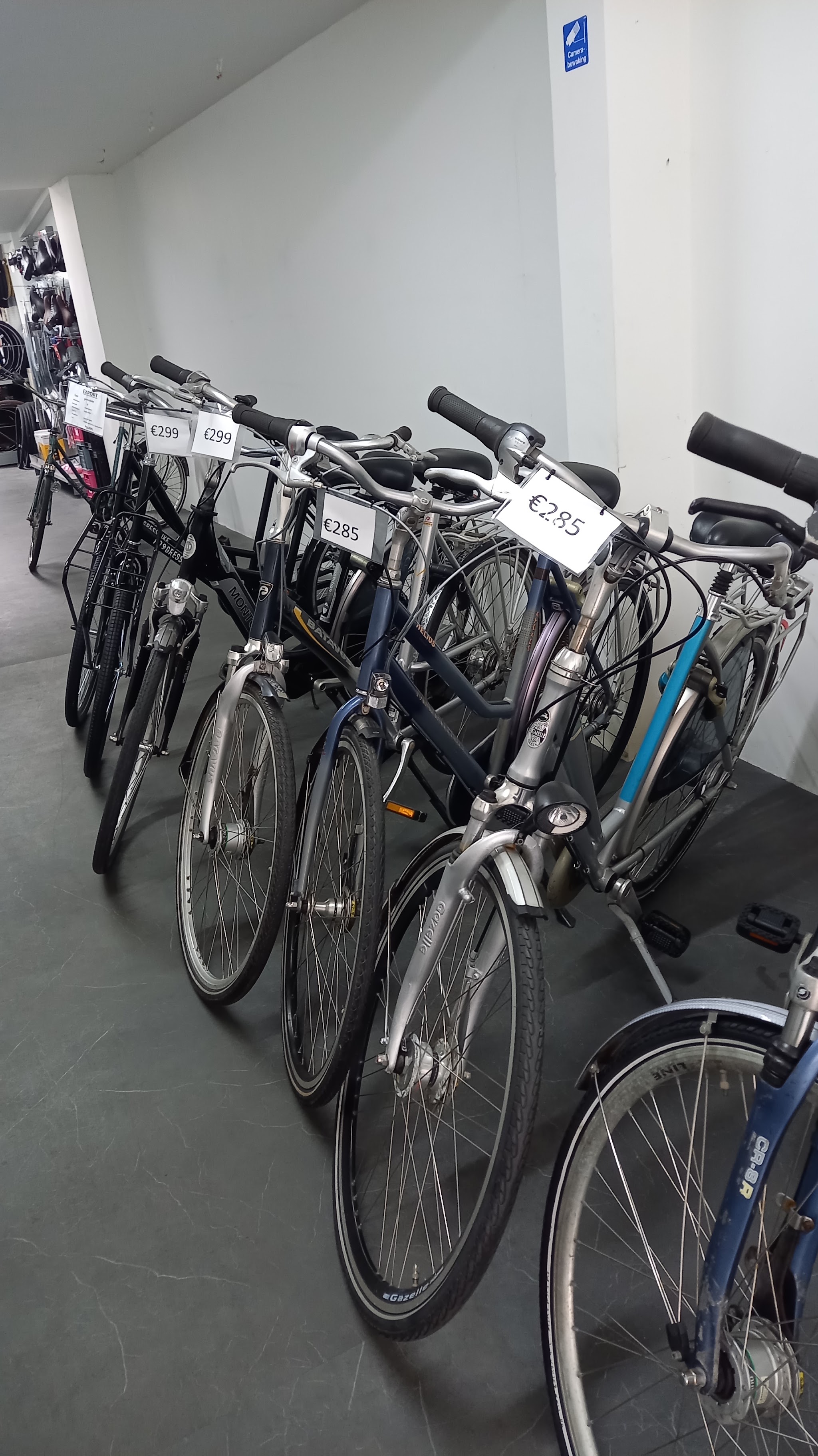 Rij tweedehands stadsfietsen van Gazelle en Batavus met prijskaartjes in de winkel